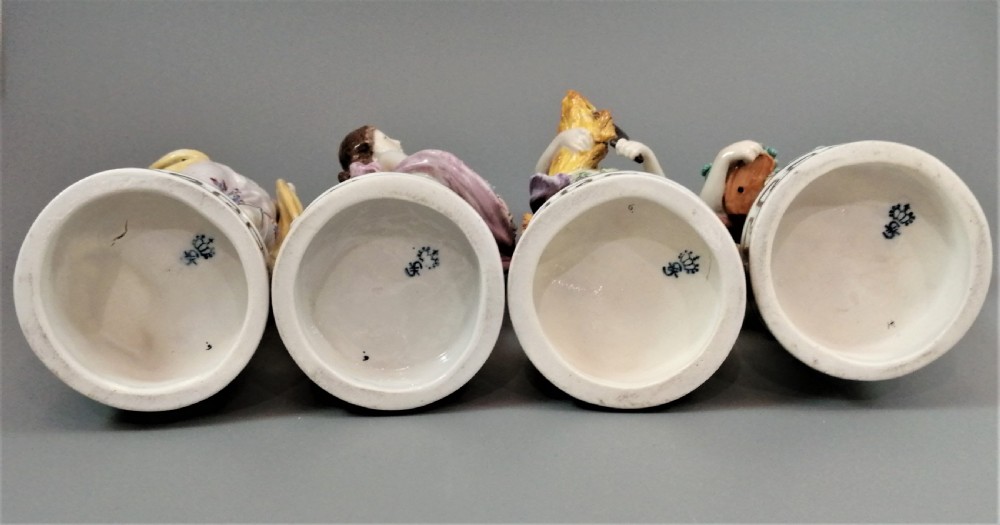 A set of four Sitzendorf polychrome glazed porcelain figurines representing allegories of the Four Seasons, standing on cylindrical Greek key patterned bases. View X