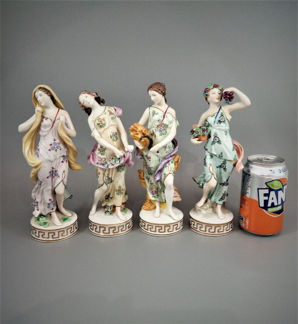 A set of four Sitzendorf polychrome glazed porcelain figurines representing allegories of the Four Seasons, standing on cylindrical Greek key patterned bases. View XI