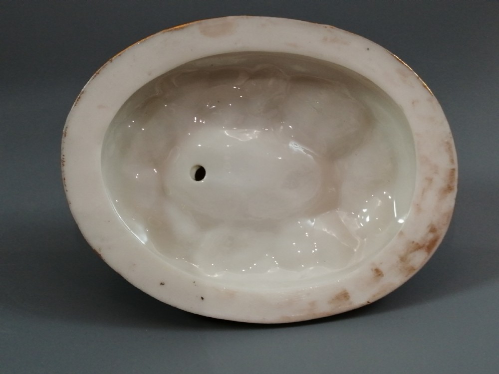 A 19th-century majolica ceramic figurine depicting a figure seated in a small boat over green waves, mounted on a pink glazed oval base with gilded borders. View X