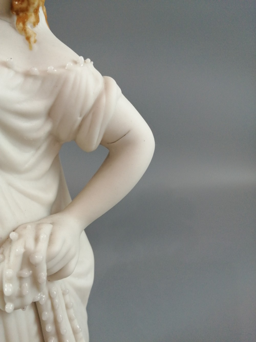 A nineteenth-century Victorian Parian ware figurine depicting a classically draped maiden holding a fruit basket on her shoulder. View IX