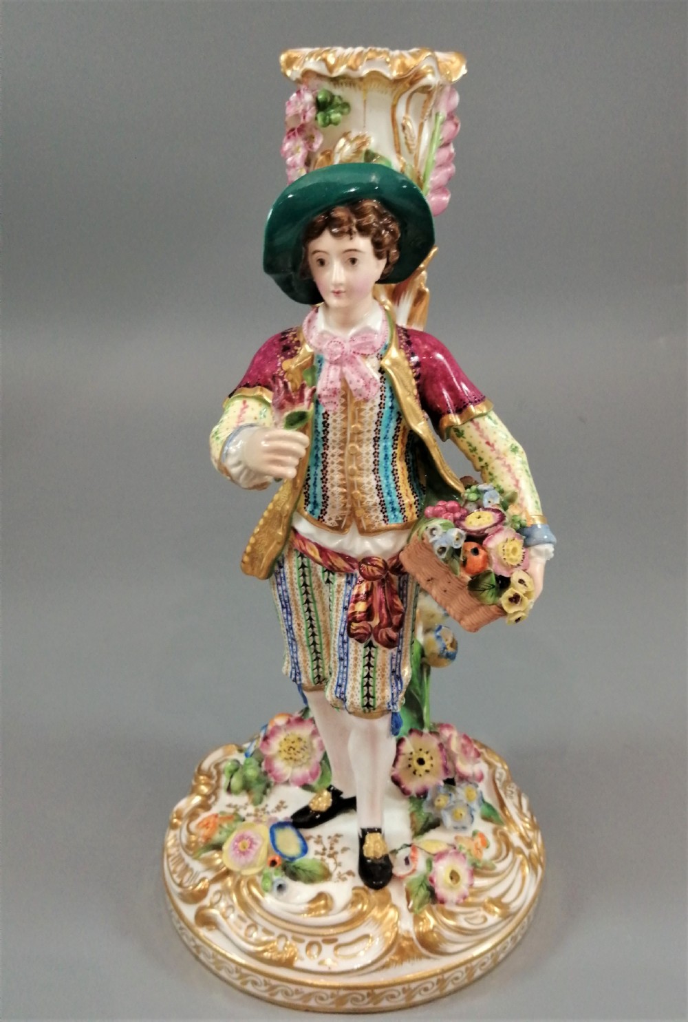 A pair of hand-painted Minton porcelain figural candlesticks featuring a male and female figure in colourful traditional dress with floral motifs and gilded scroll bases. View V
