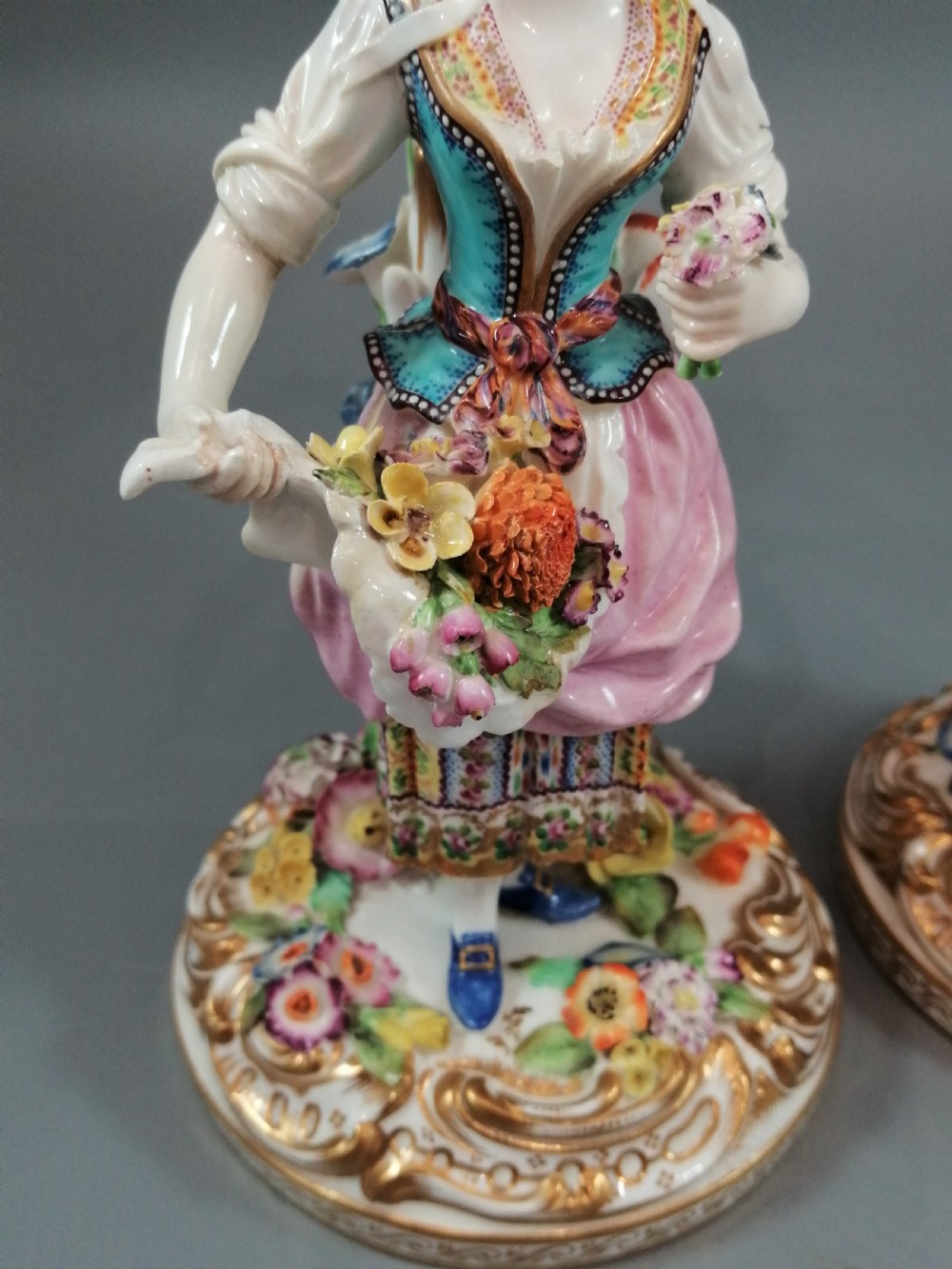 A pair of hand-painted Minton porcelain figural candlesticks featuring a male and female figure in colourful traditional dress with floral motifs and gilded scroll bases. View IX
