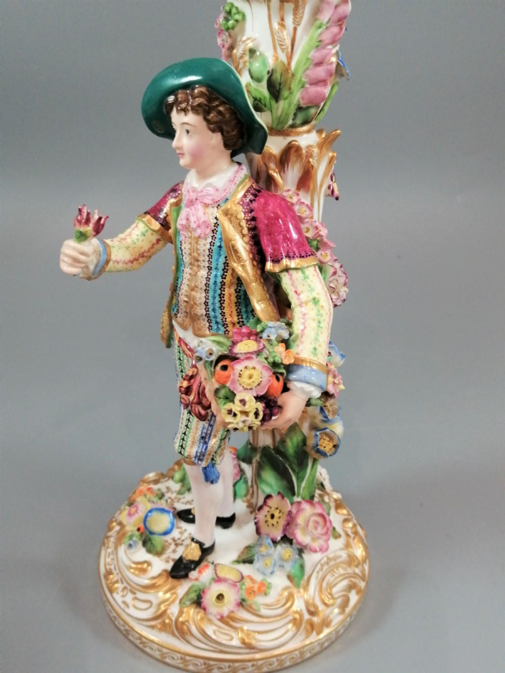 A pair of hand-painted Minton porcelain figural candlesticks featuring a male and female figure in colourful traditional dress with floral motifs and gilded scroll bases. View XI