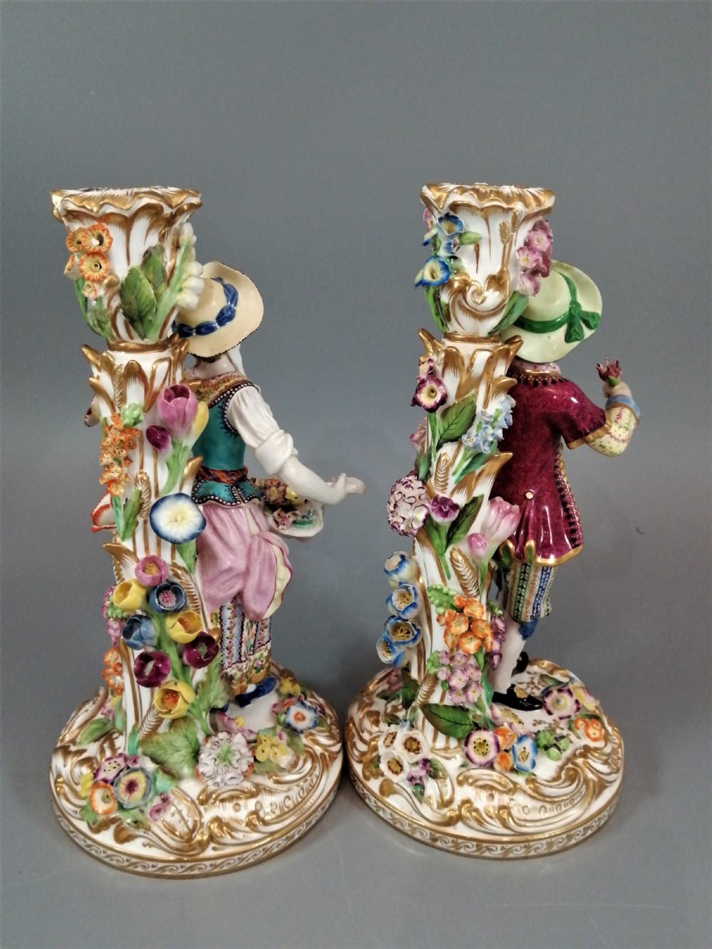 A pair of hand-painted Minton porcelain figural candlesticks featuring a male and female figure in colourful traditional dress with floral motifs and gilded scroll bases. View XV