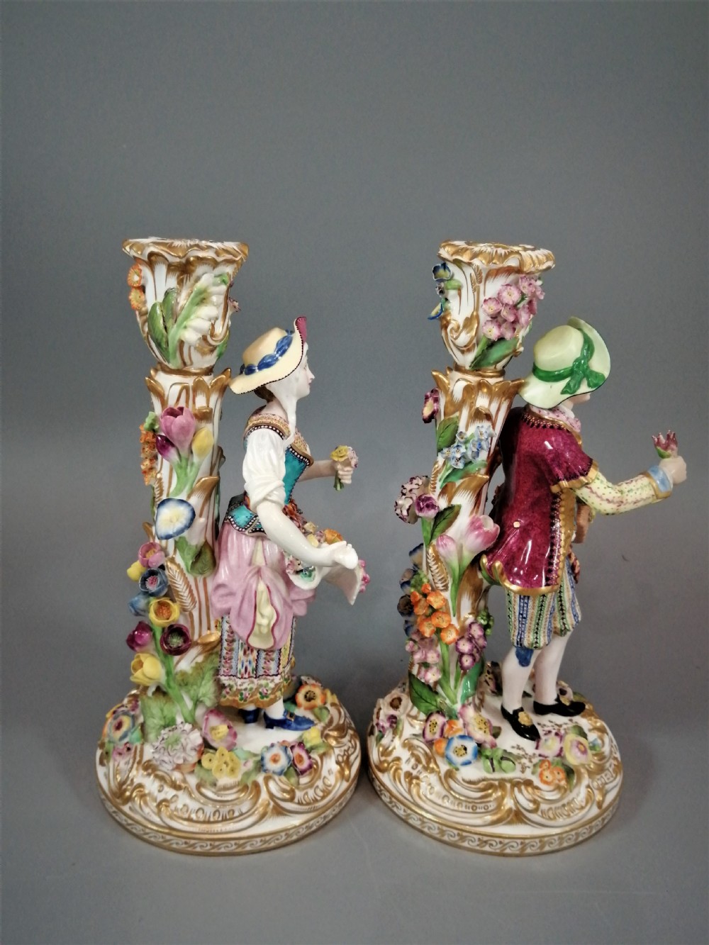 A pair of hand-painted Minton porcelain figural candlesticks featuring a male and female figure in colourful traditional dress with floral motifs and gilded scroll bases. View XVI