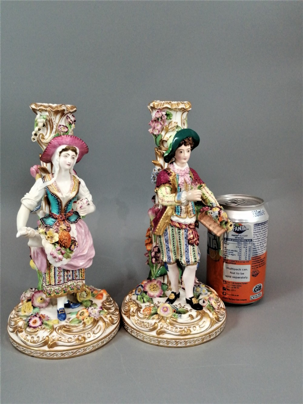 A pair of hand-painted Minton porcelain figural candlesticks featuring a male and female figure in colourful traditional dress with floral motifs and gilded scroll bases. View XIX