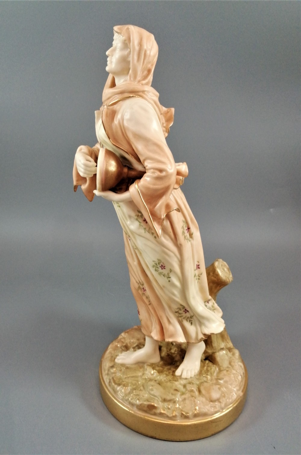 A late Victorian Royal Worcester porcelain figurine depicting a standing female musician in draped robes holding a hand drum. View IV