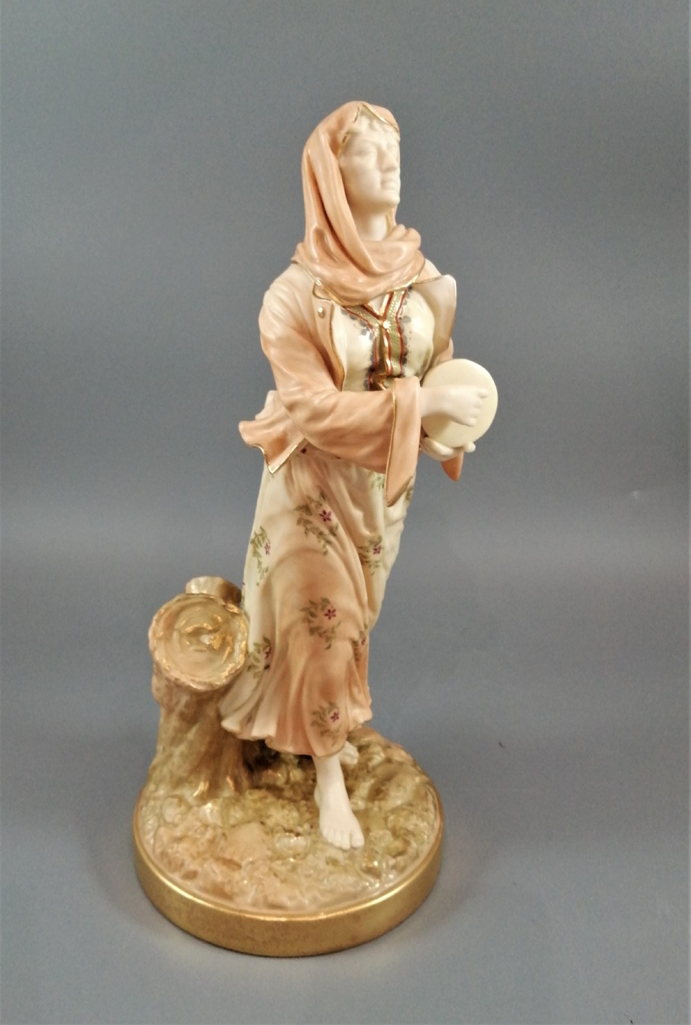 A late Victorian Royal Worcester porcelain figurine depicting a standing female musician in draped robes holding a hand drum. View VII