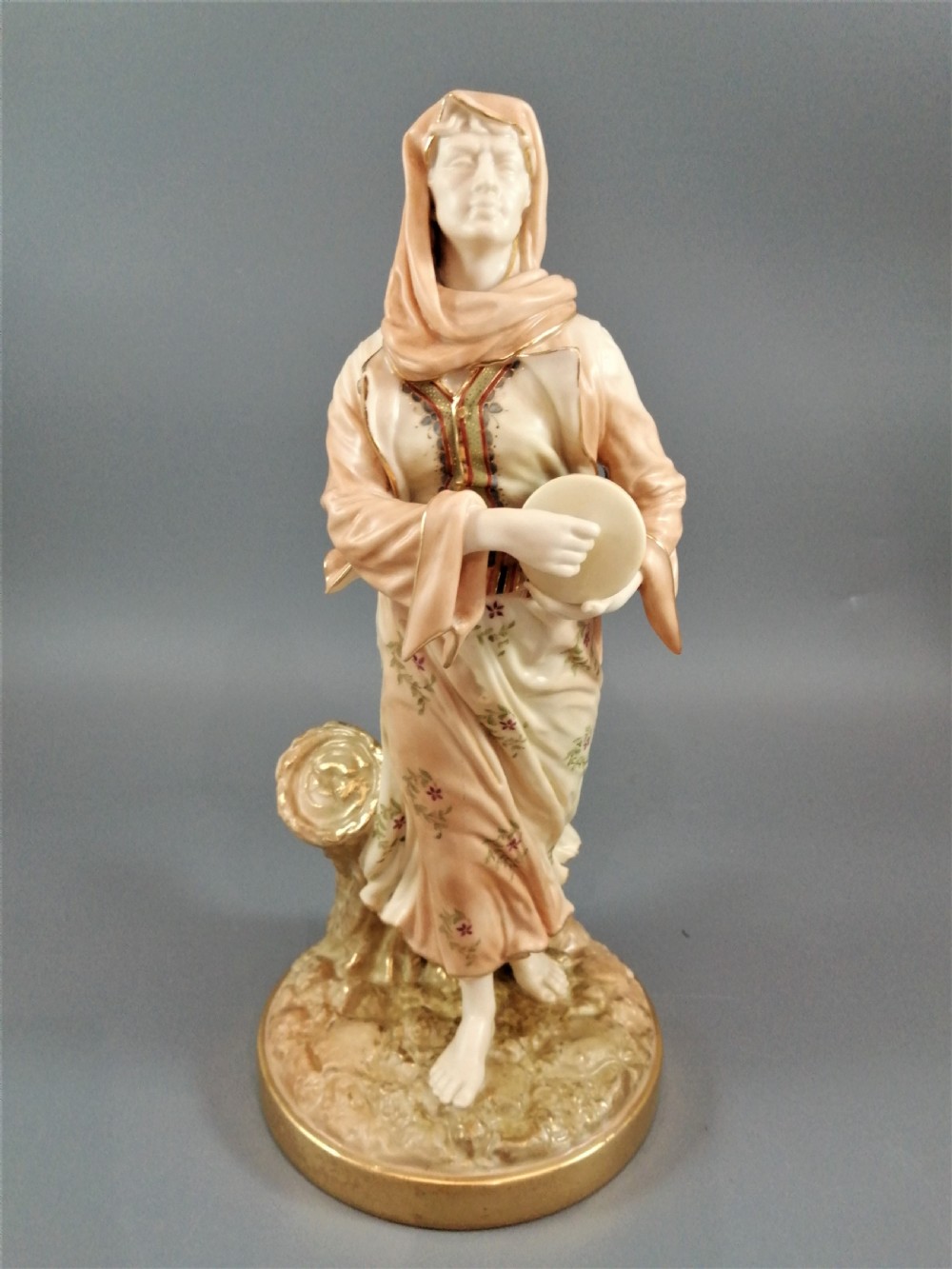 A late Victorian Royal Worcester porcelain figurine depicting a standing female musician in draped robes holding a hand drum. View VIII