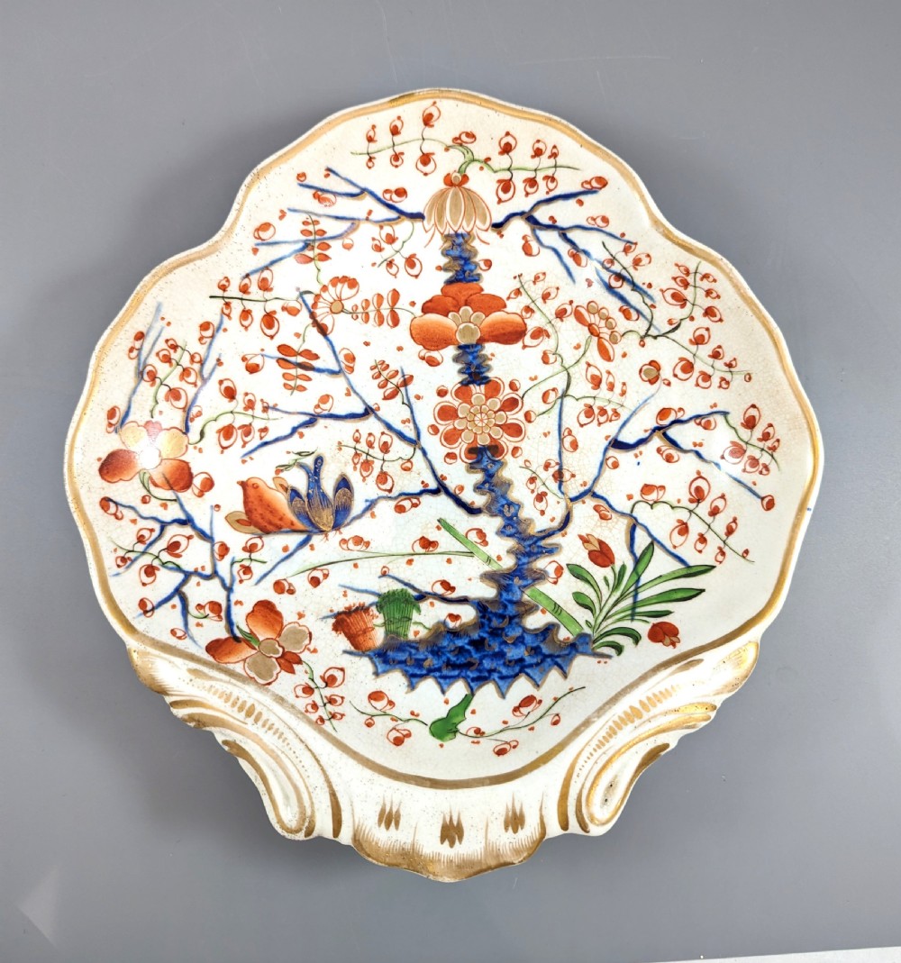 An antique shell-shaped porcelain plate featuring hand-painted Kakiemon-style motifs of two quails beneath flowering branches with gilt highlights.