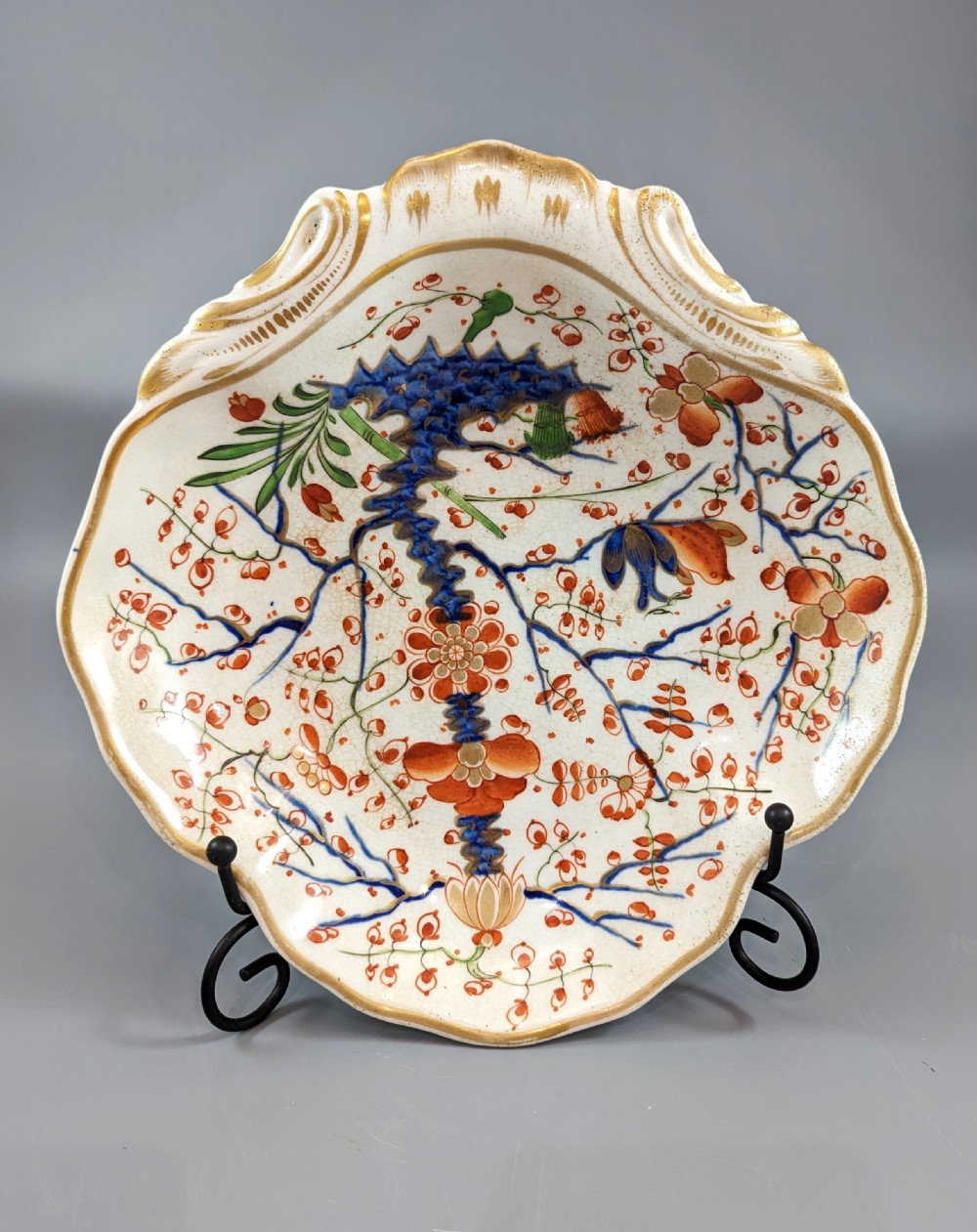 An antique shell-shaped porcelain plate featuring hand-painted Kakiemon-style motifs of two quails beneath flowering branches with gilt highlights. View II