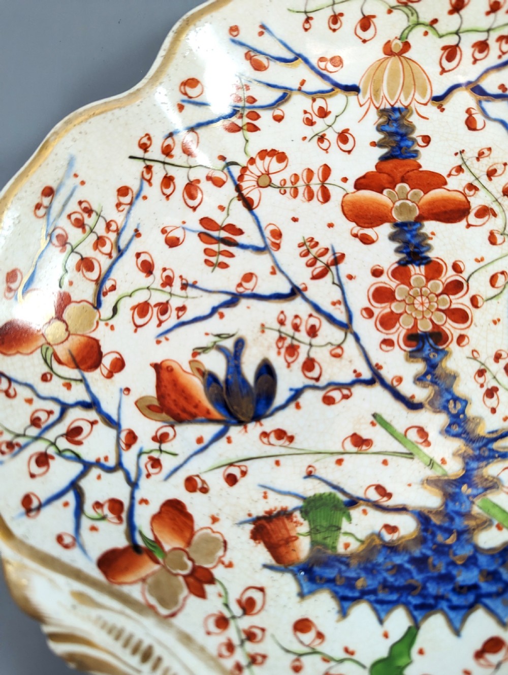An antique shell-shaped porcelain plate featuring hand-painted Kakiemon-style motifs of two quails beneath flowering branches with gilt highlights. View IV