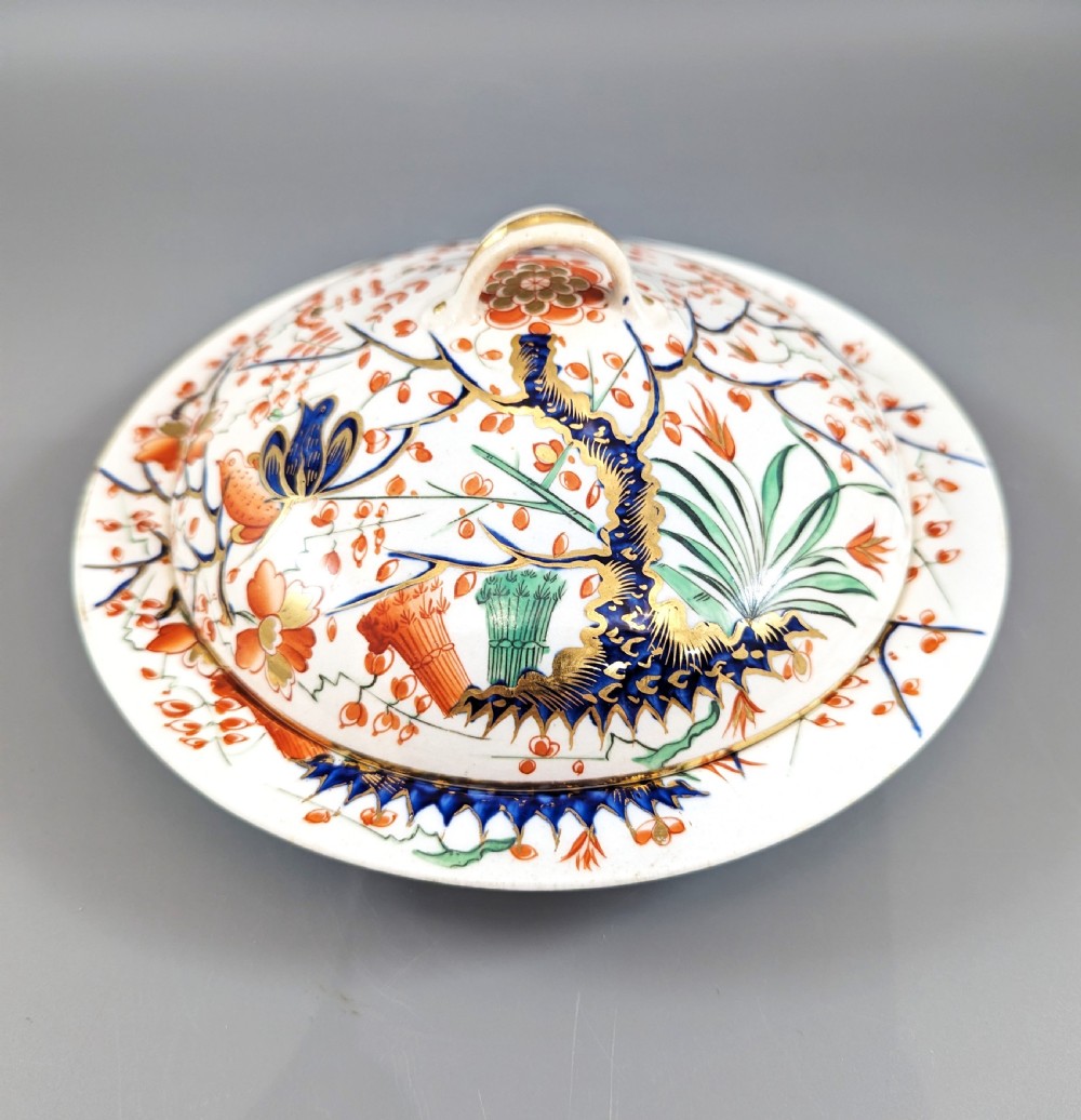 A circular antique porcelain butter dish with stand, decorated with hand-painted Japanese Kakiemon style quail and floral motifs in iron-red, blue, and gold. View II