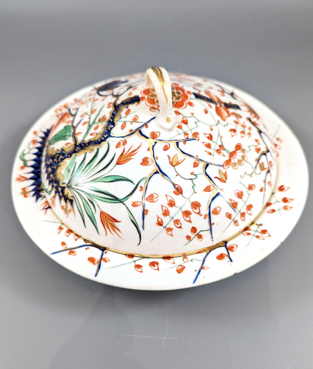 A circular antique porcelain butter dish with stand, decorated with hand-painted Japanese Kakiemon style quail and floral motifs in iron-red, blue, and gold. View III