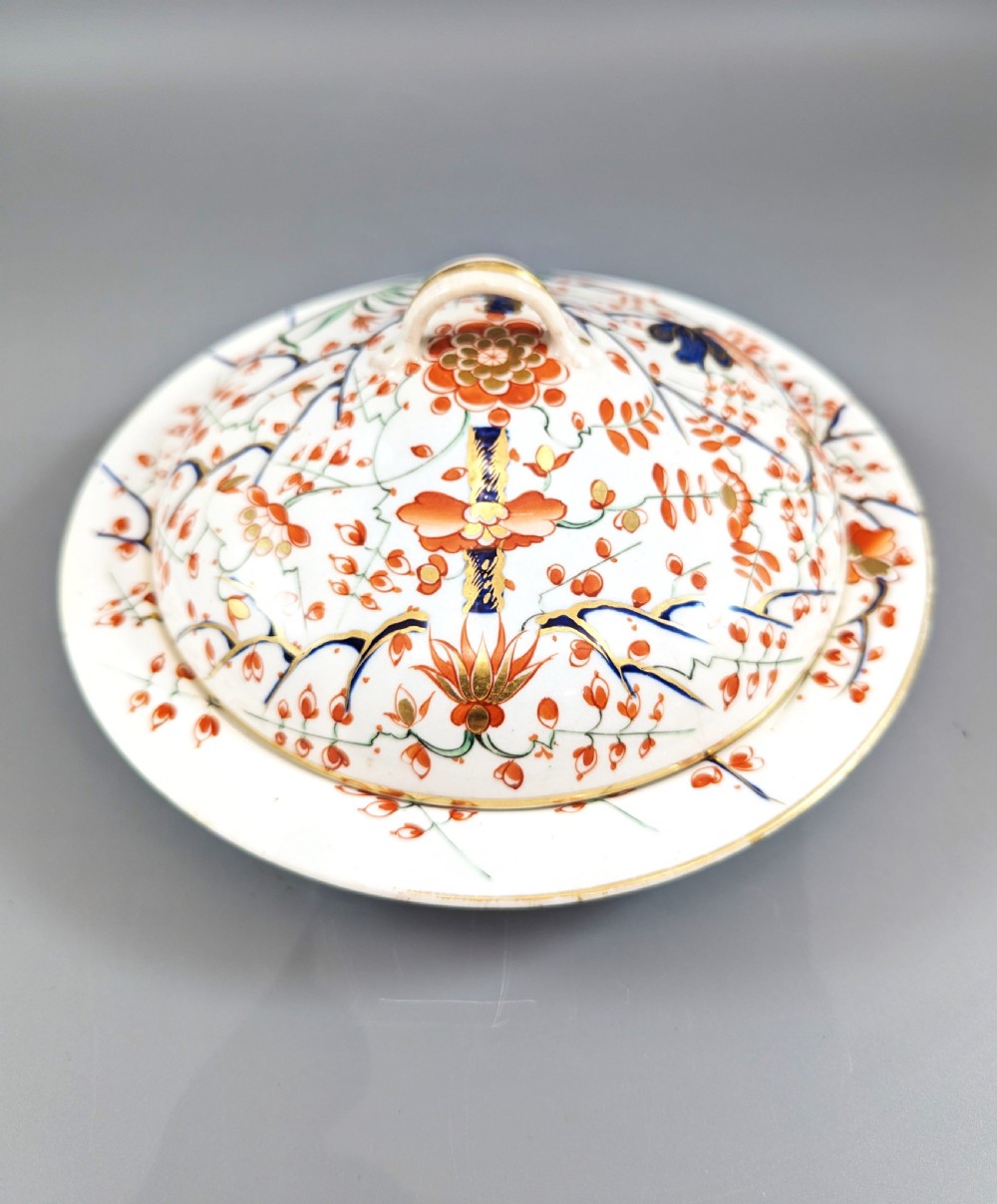A circular antique porcelain butter dish with stand, decorated with hand-painted Japanese Kakiemon style quail and floral motifs in iron-red, blue, and gold. View V