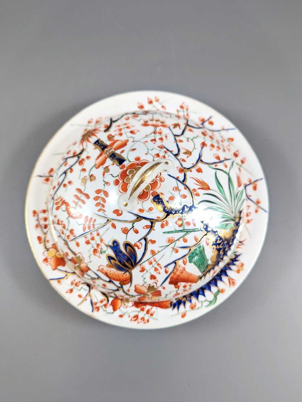 A circular antique porcelain butter dish with stand, decorated with hand-painted Japanese Kakiemon style quail and floral motifs in iron-red, blue, and gold. View VI