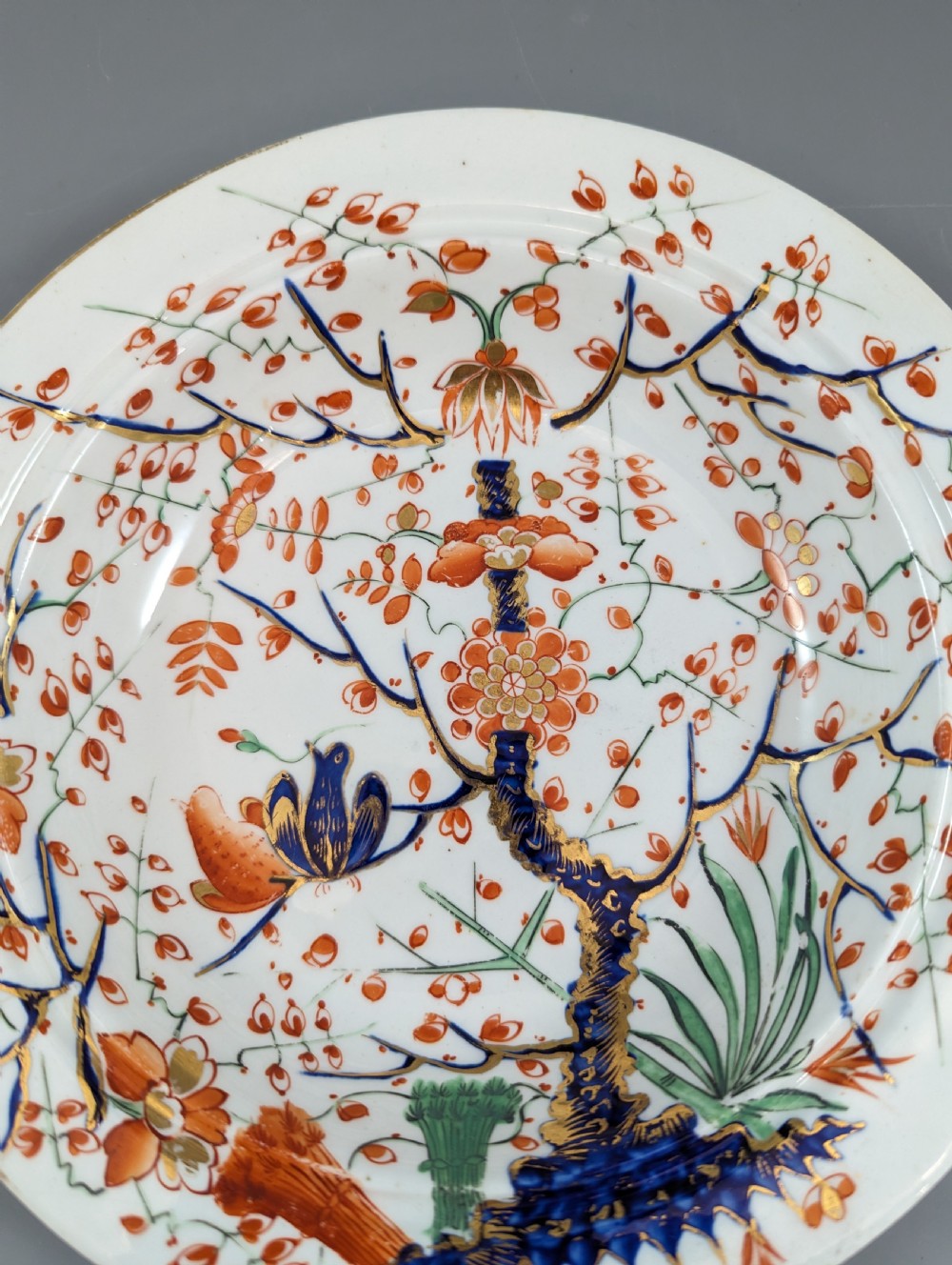 A circular antique porcelain butter dish with stand, decorated with hand-painted Japanese Kakiemon style quail and floral motifs in iron-red, blue, and gold. View IX