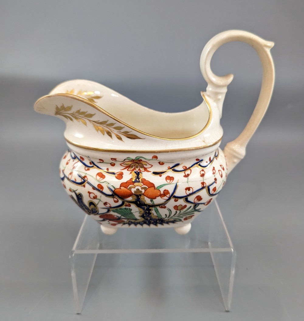 An antique cream-coloured porcelain jug featuring a hand-painted Two Quails design with gilded rim detailing and a raised loop handle.