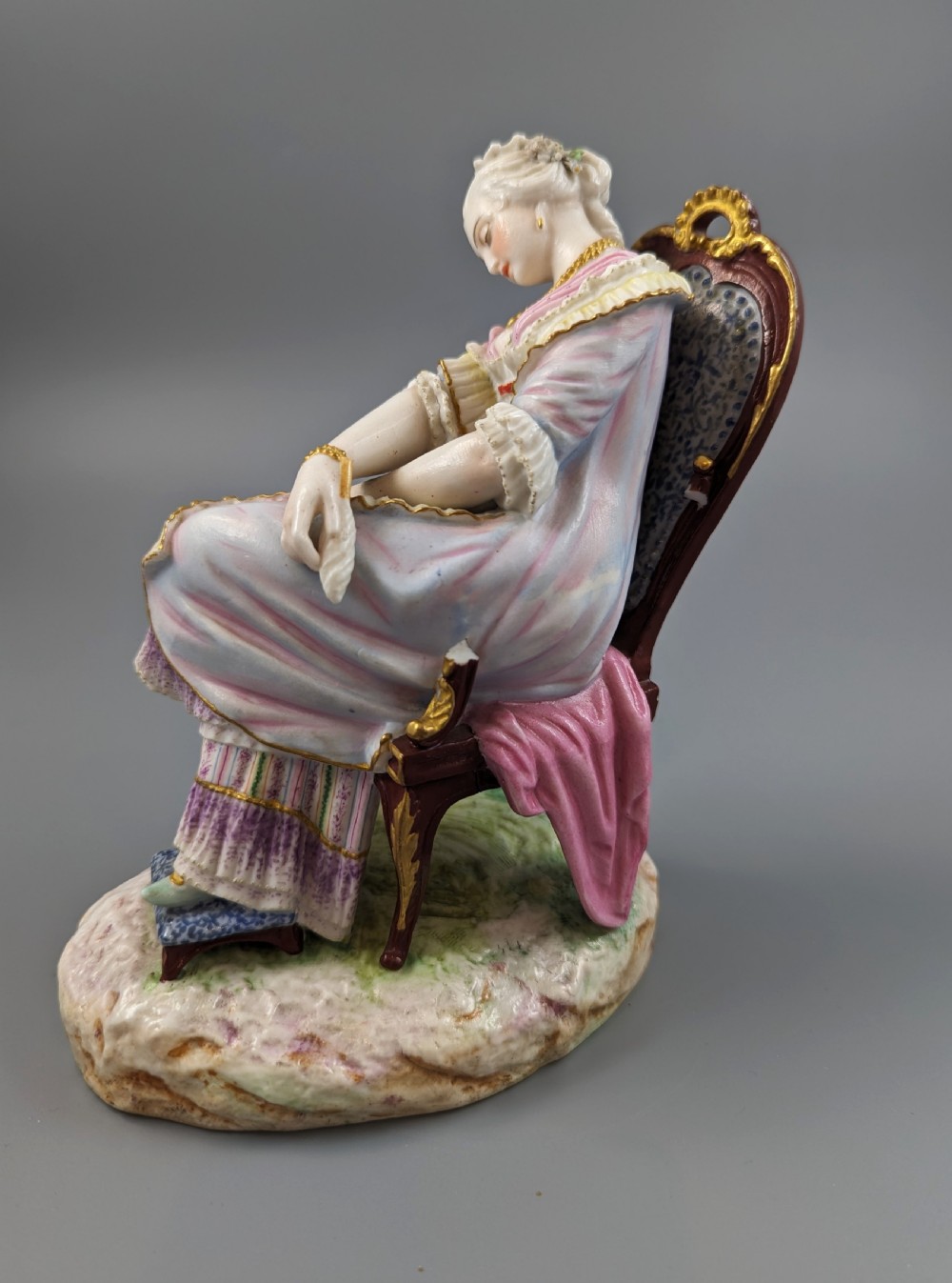 A 19th-century French biscuit porcelain figurine depicting a sleeping lady seated in a chair with pastel pink drapery and gold accents. View II