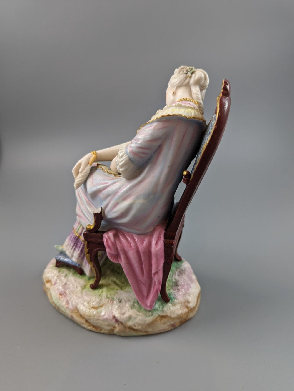 A 19th-century French biscuit porcelain figurine depicting a sleeping lady seated in a chair with pastel pink drapery and gold accents. View III