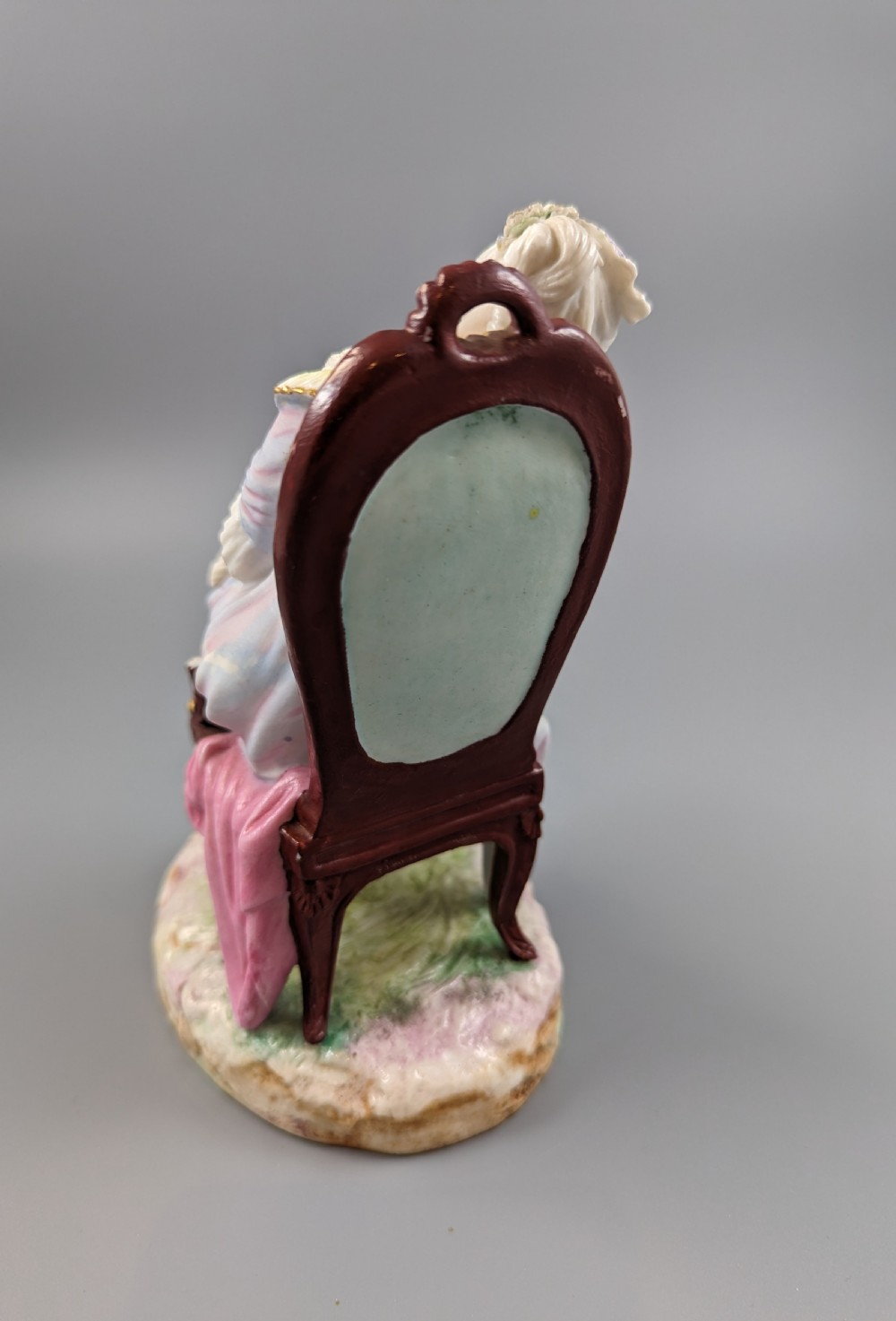 A 19th-century French biscuit porcelain figurine depicting a sleeping lady seated in a chair with pastel pink drapery and gold accents. View IV