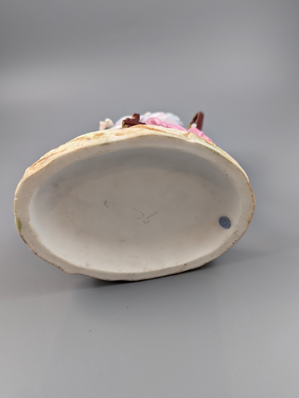 A 19th-century French biscuit porcelain figurine depicting a sleeping lady seated in a chair with pastel pink drapery and gold accents. View VI