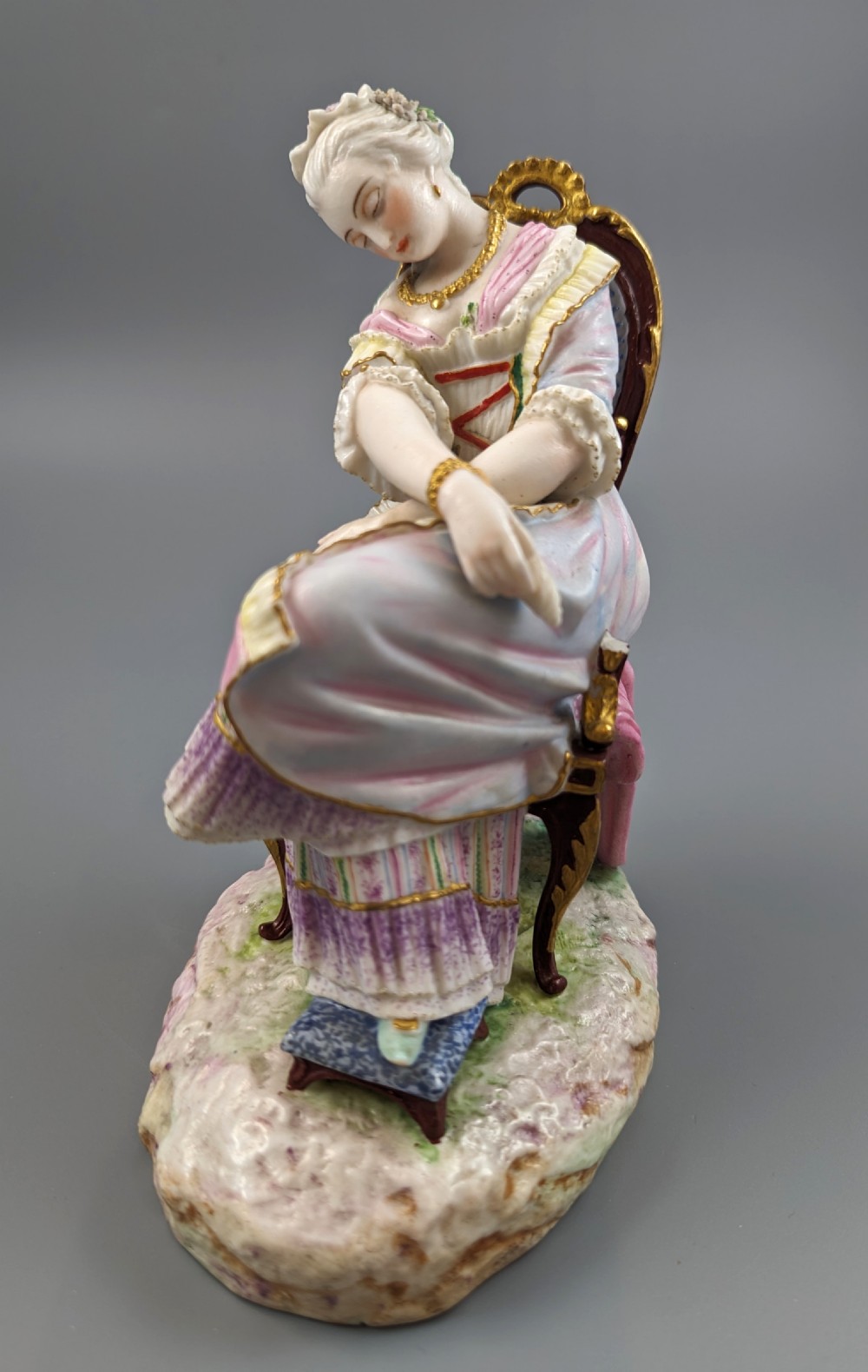 A 19th-century French biscuit porcelain figurine depicting a sleeping lady seated in a chair with pastel pink drapery and gold accents. View VII
