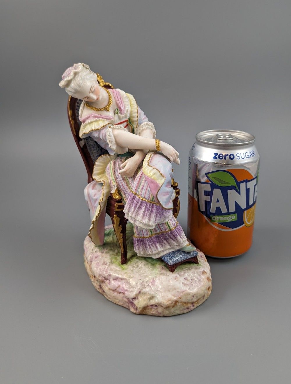 A 19th-century French biscuit porcelain figurine depicting a sleeping lady seated in a chair with pastel pink drapery and gold accents. View XI