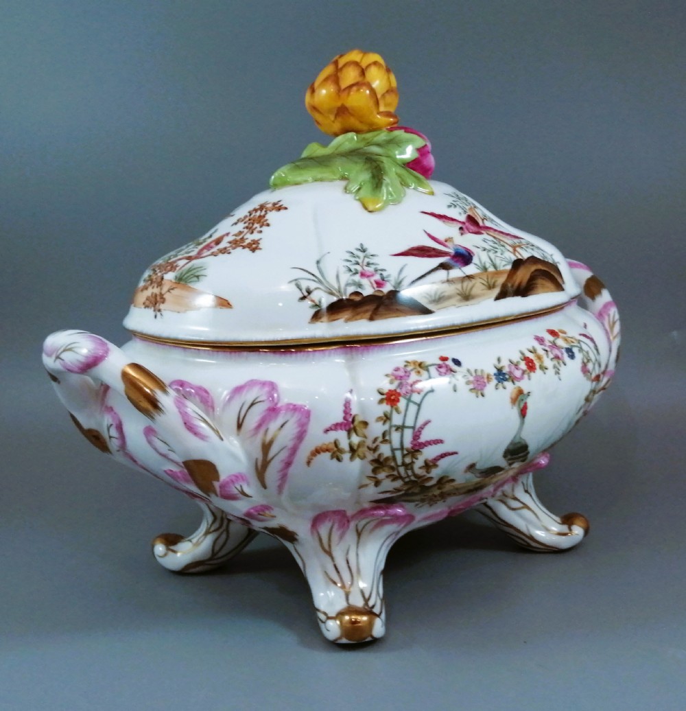 An antique continental porcelain soup tureen with a fruit finial lid, dual handles, and matching underplate, decorated with hand-painted birds and gilded scrollwork. View VI