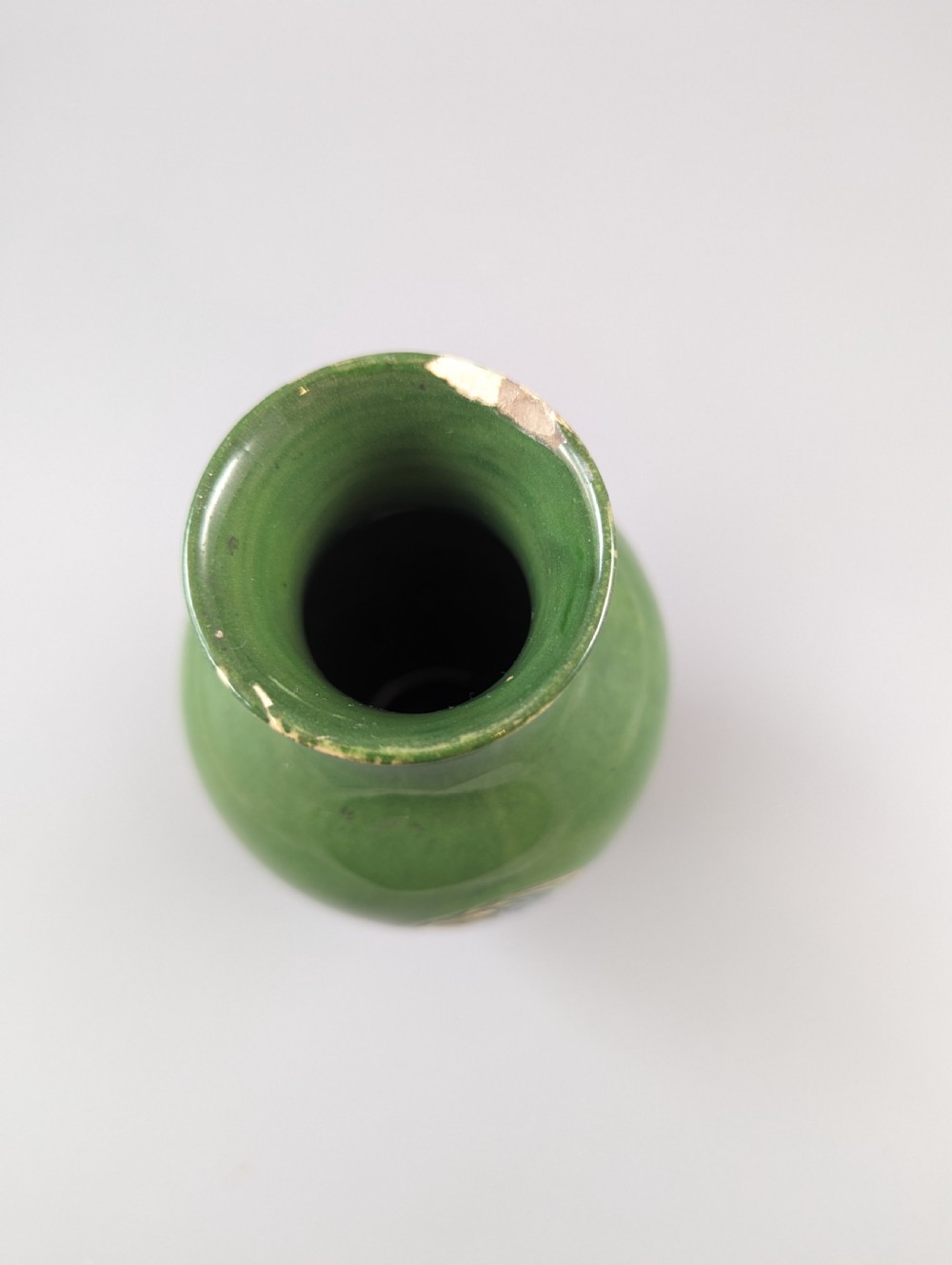 A green glazed ceramic vase with a flared neck and a central circular slip-trailed medallion featuring a stylized motif in blue, green, and cream. View VIII