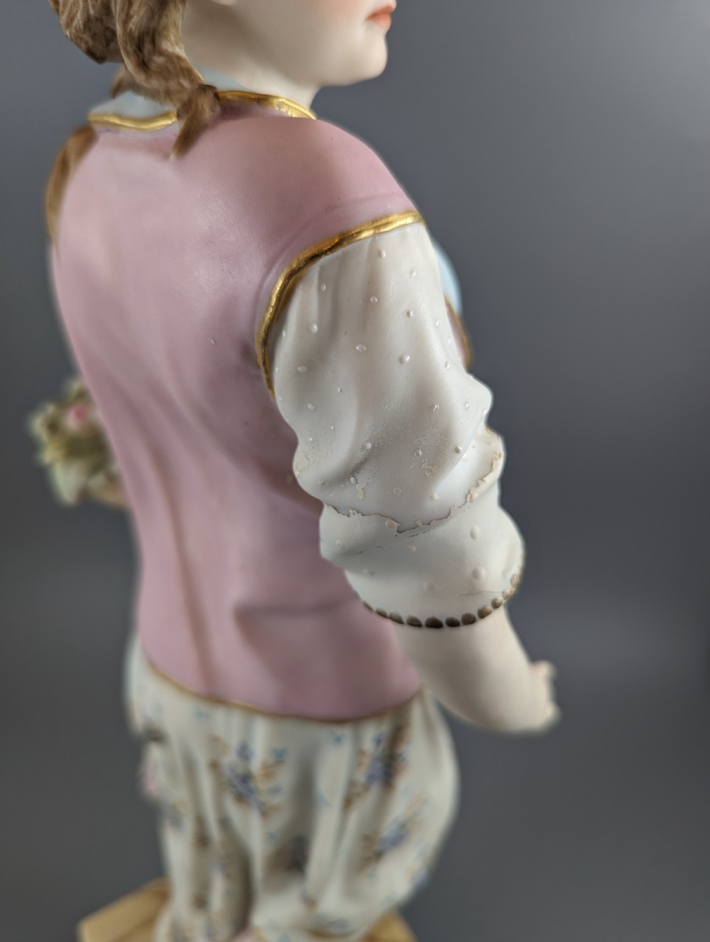 A Victorian coloured Parian porcelain figure depicting a draped female figure holding a basket of flowers on a faux-marble painted base. View VIII