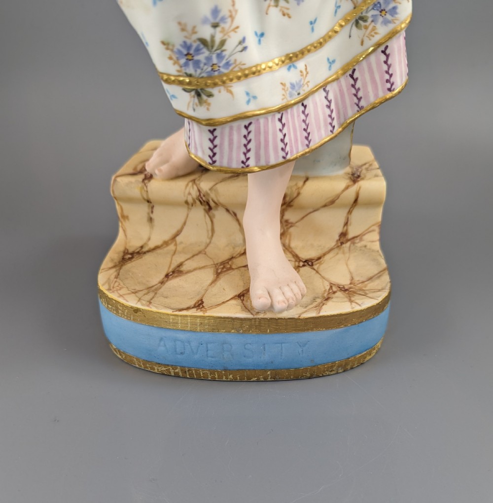 A Victorian coloured Parian porcelain figure depicting a draped female figure holding a basket of flowers on a faux-marble painted base. View X