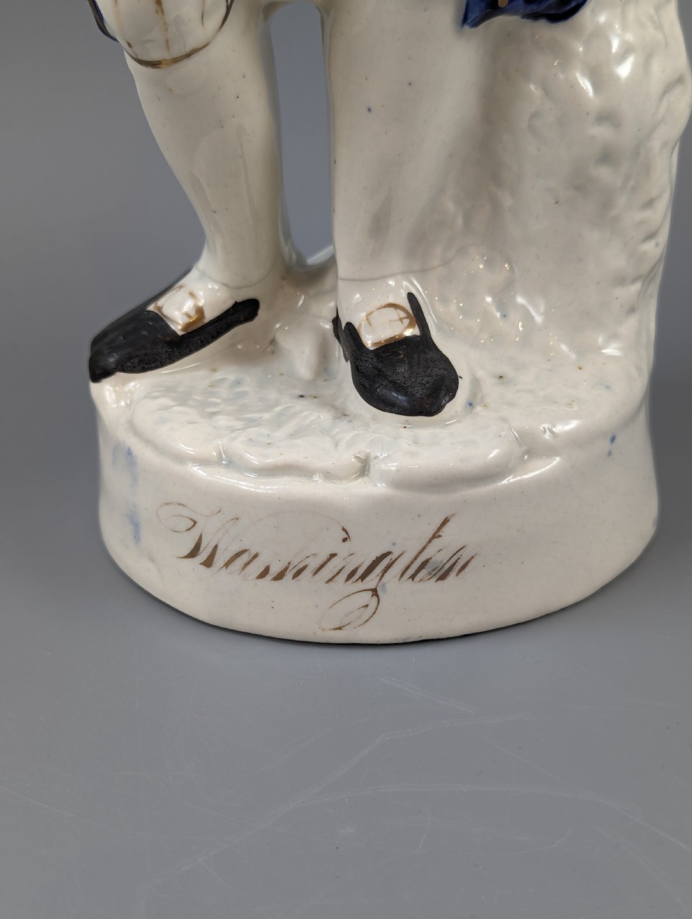 A Victorian Staffordshire earthenware figure of Benjamin Franklin standing in a cobalt blue coat and holding a tricorn hat, set on a pedestal inscribed Washington. View II