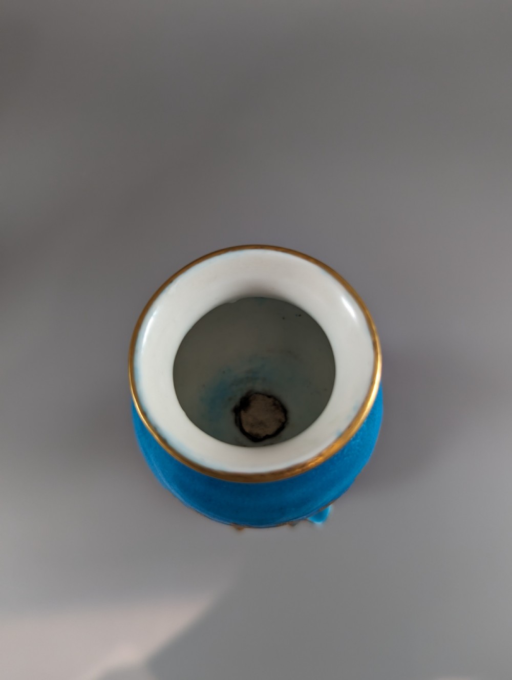 A pair of turquoise blue glazed porcelain candlesticks shaped as cherubs supporting urn sockets on fluted bases with gold trim. View XIII
