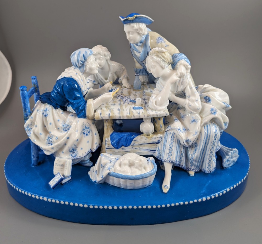 Late 19th-century French blue and white glazed porcelain figurine group depicting four figures gathered around a table fortune-telling on an oval blue base.