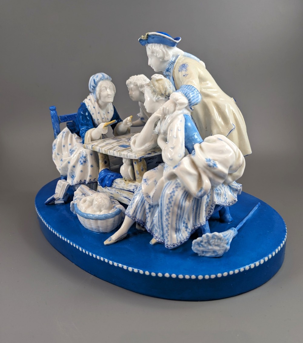 Late 19th-century French blue and white glazed porcelain figurine group depicting four figures gathered around a table fortune-telling on an oval blue base. View II