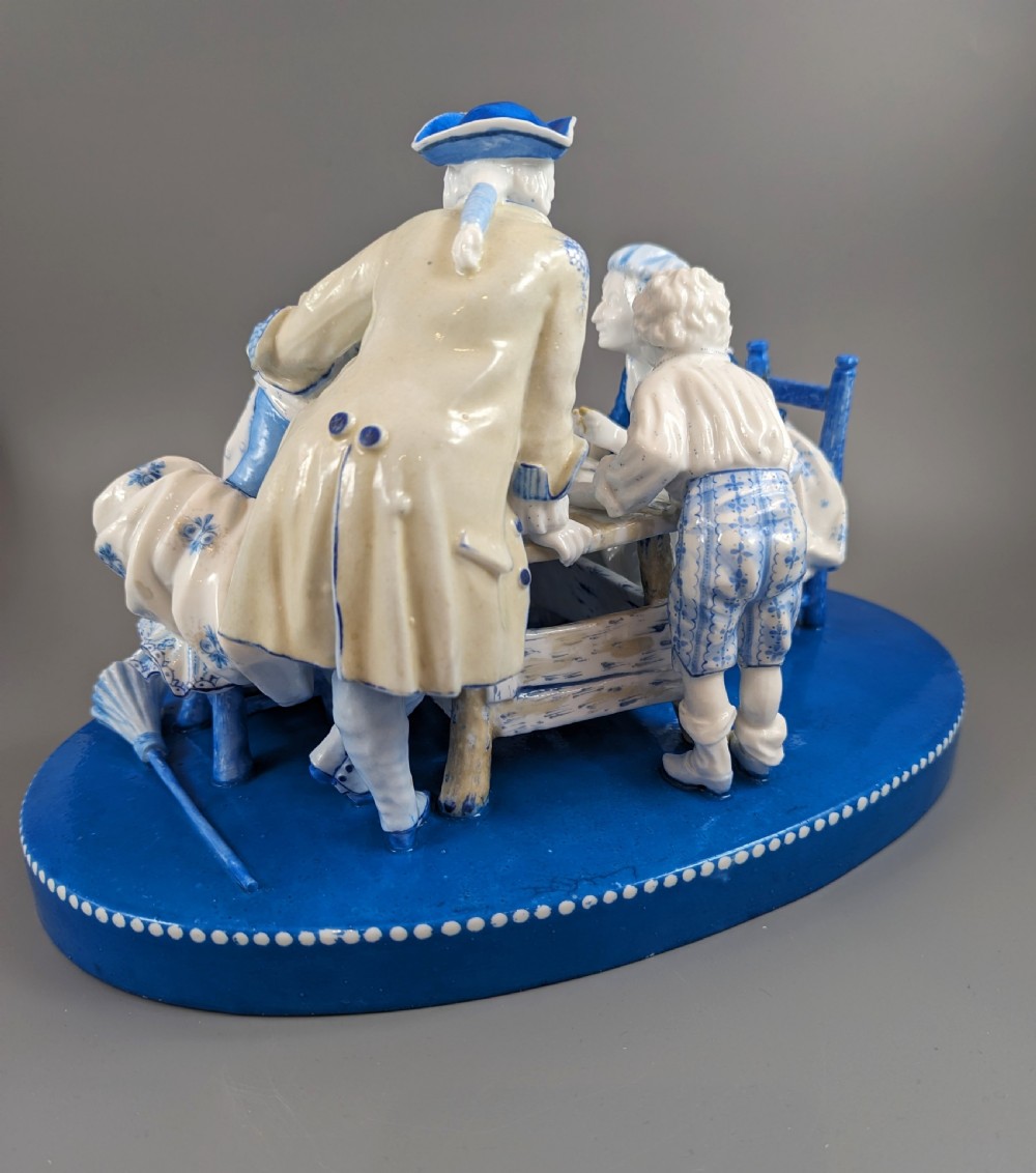 Late 19th-century French blue and white glazed porcelain figurine group depicting four figures gathered around a table fortune-telling on an oval blue base. View IV