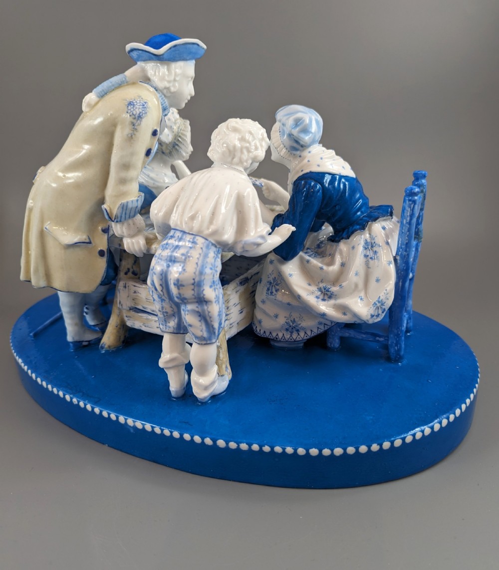 Late 19th-century French blue and white glazed porcelain figurine group depicting four figures gathered around a table fortune-telling on an oval blue base. View V