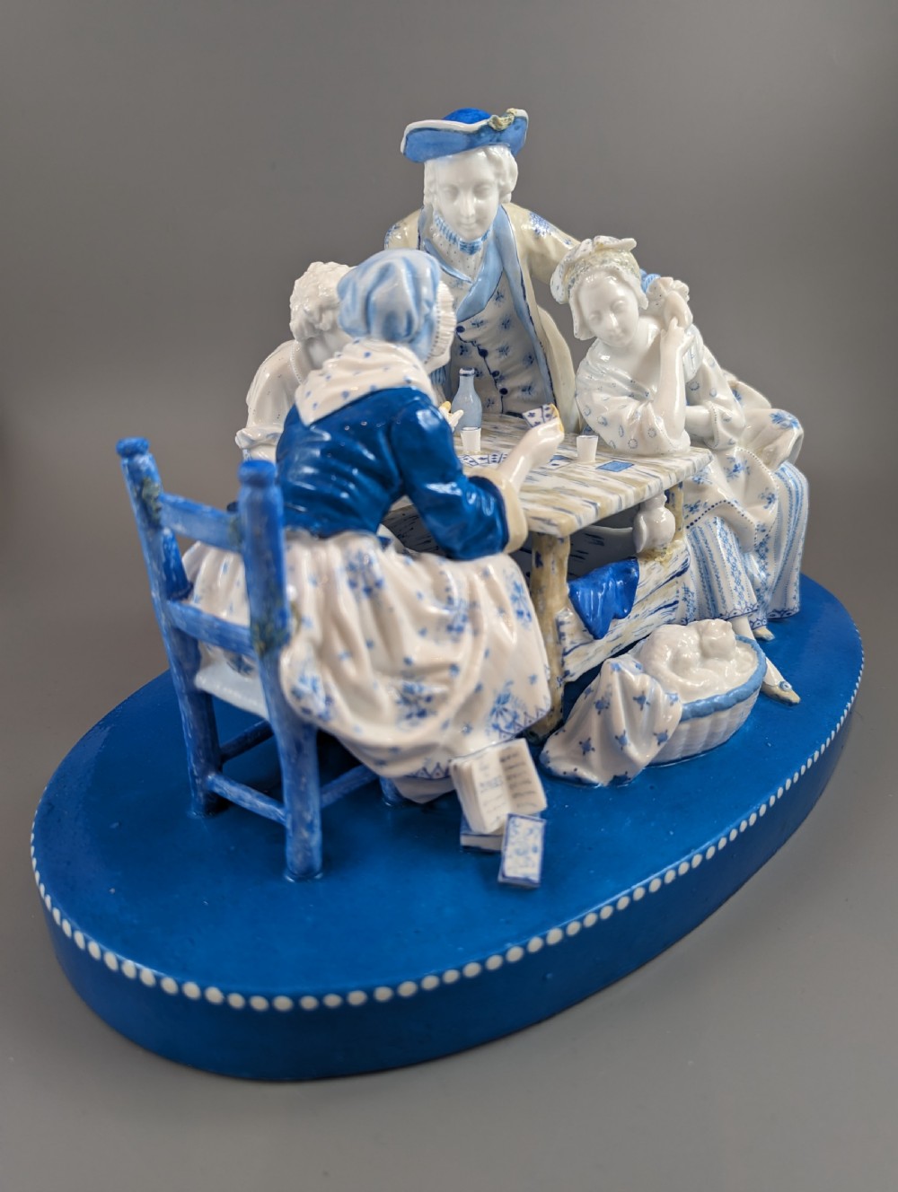 Late 19th-century French blue and white glazed porcelain figurine group depicting four figures gathered around a table fortune-telling on an oval blue base. View VIII