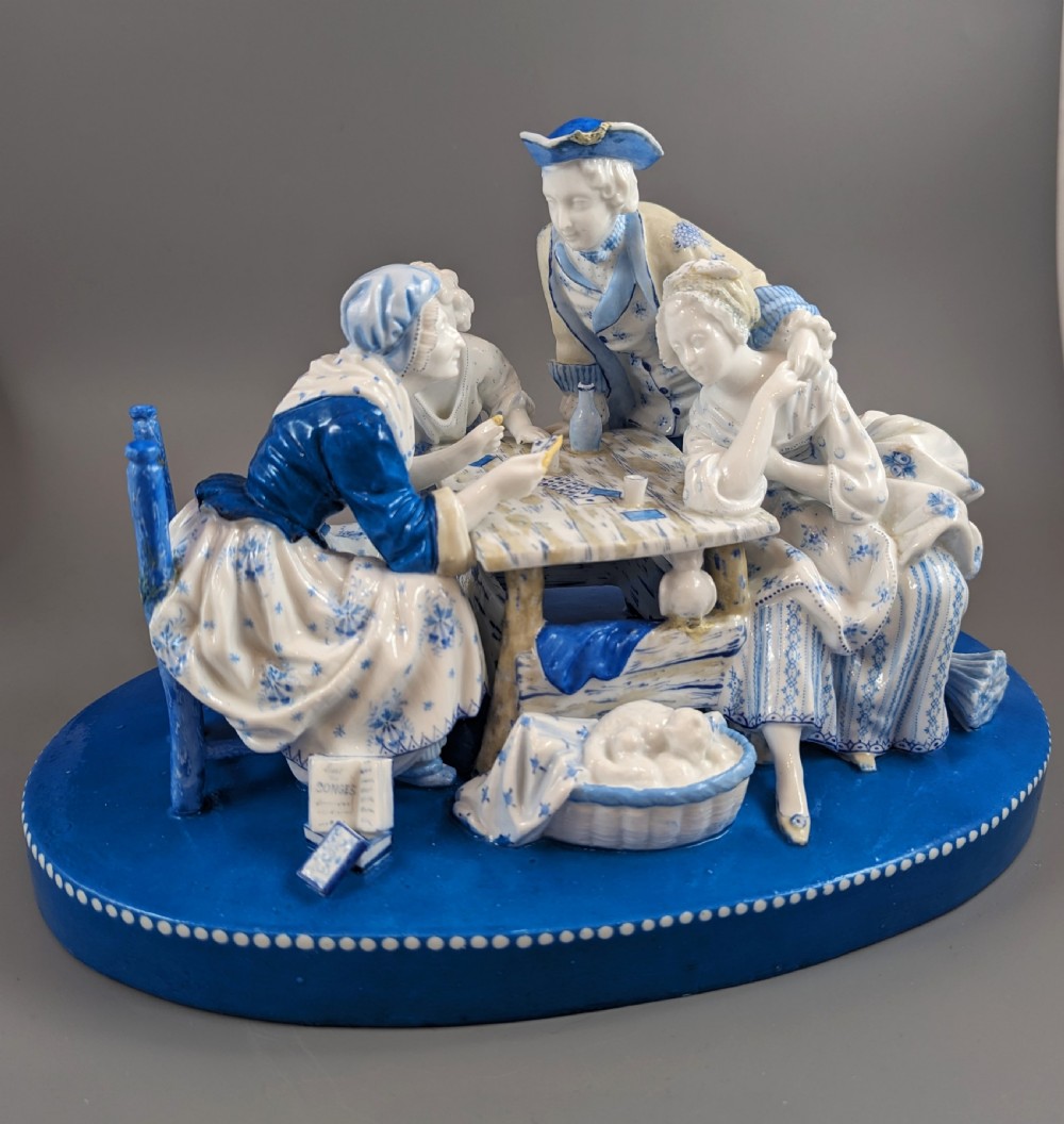 Late 19th-century French blue and white glazed porcelain figurine group depicting four figures gathered around a table fortune-telling on an oval blue base. View IX