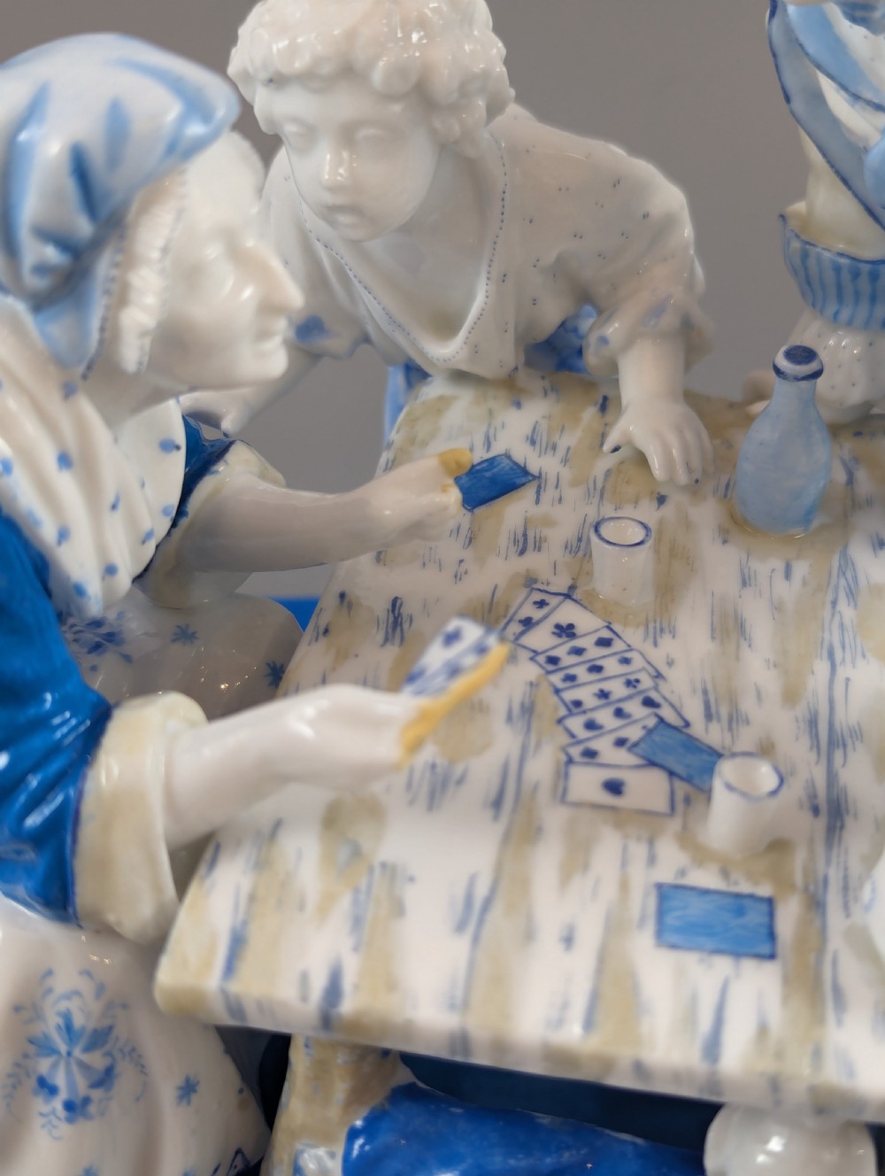 Late 19th-century French blue and white glazed porcelain figurine group depicting four figures gathered around a table fortune-telling on an oval blue base. View XIII