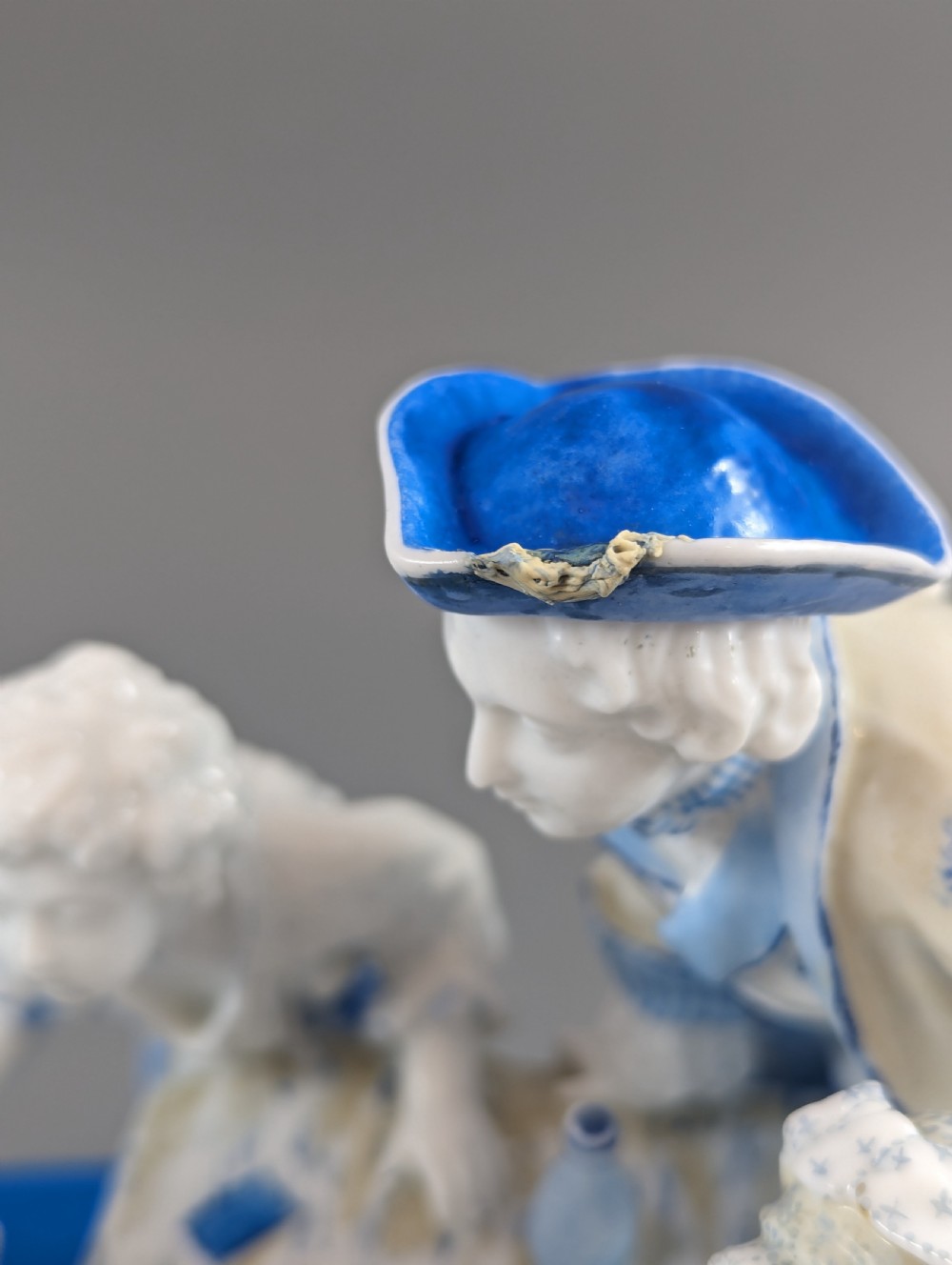 Late 19th-century French blue and white glazed porcelain figurine group depicting four figures gathered around a table fortune-telling on an oval blue base. View XIV