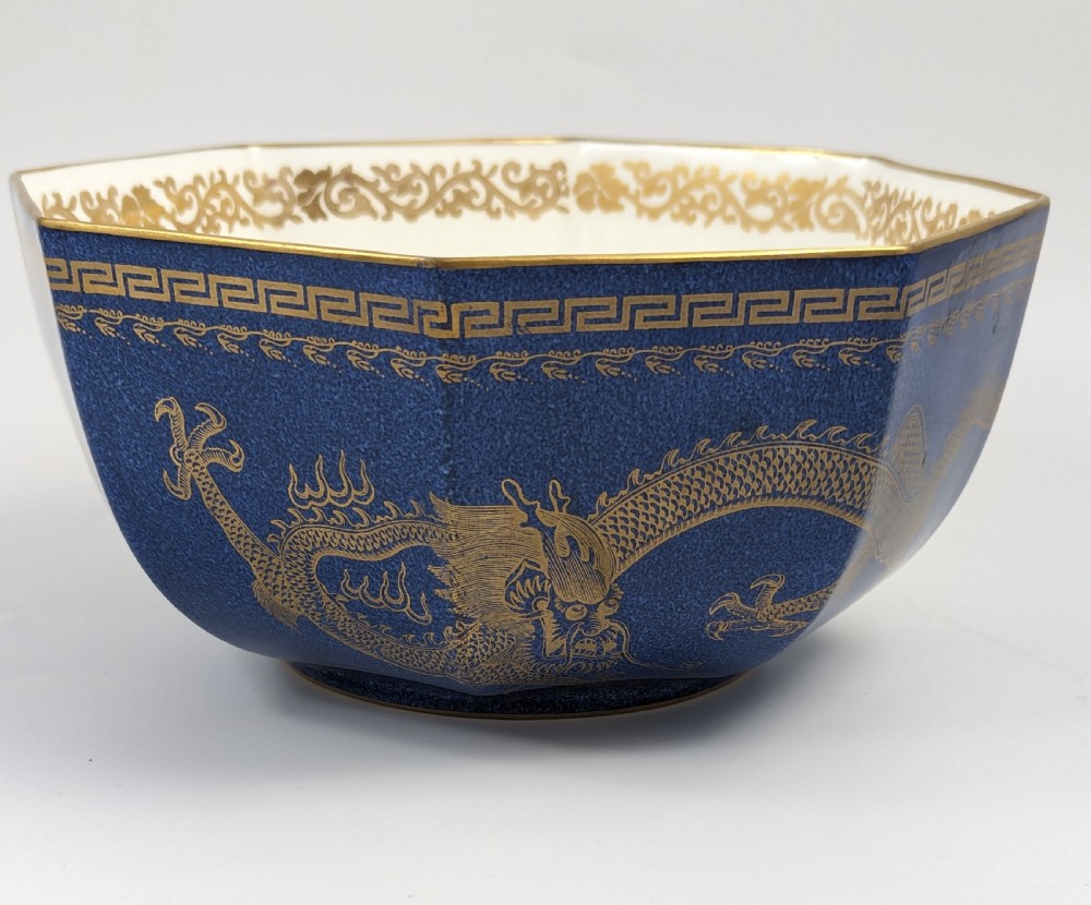 An octagonal cobalt blue ceramic bowl featuring gilded celestial dragon motifs and a Greek key upper rim.