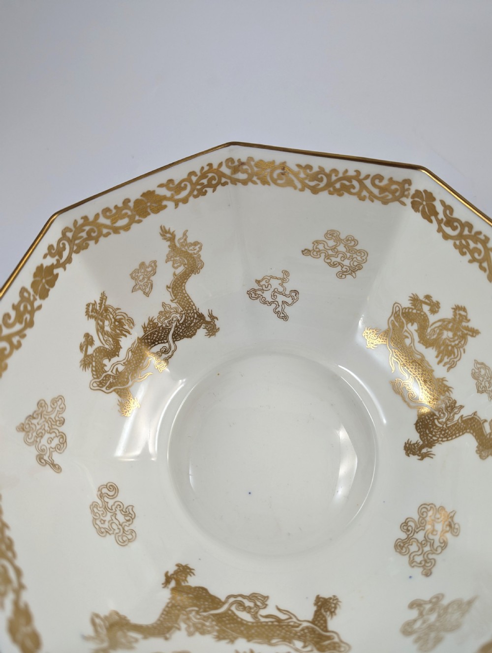 An octagonal cobalt blue ceramic bowl featuring gilded celestial dragon motifs and a Greek key upper rim. View XIV