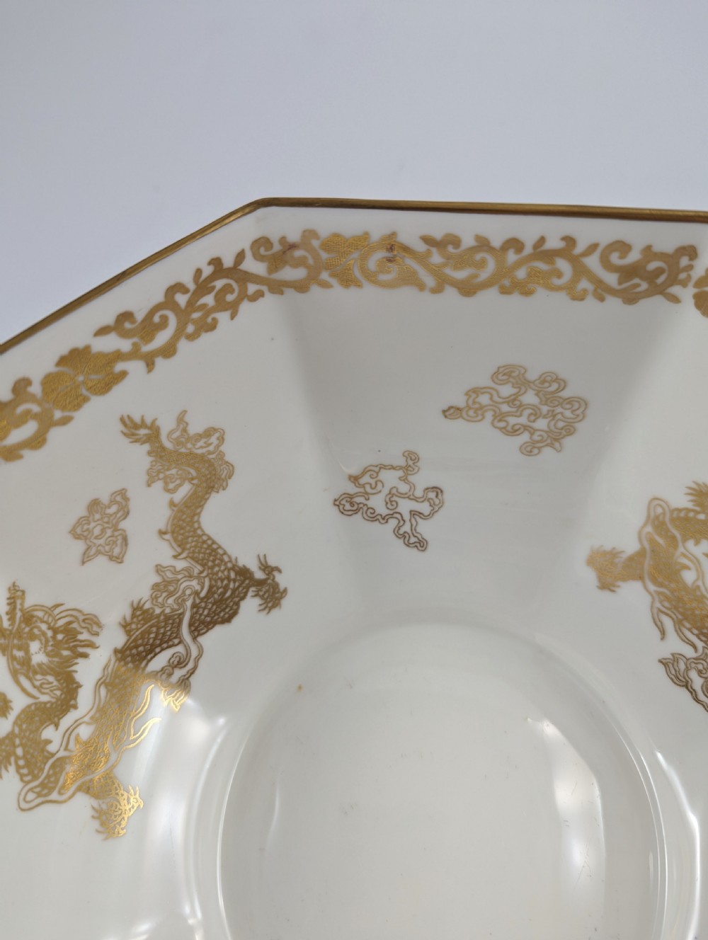 An octagonal cobalt blue ceramic bowl featuring gilded celestial dragon motifs and a Greek key upper rim. View XV