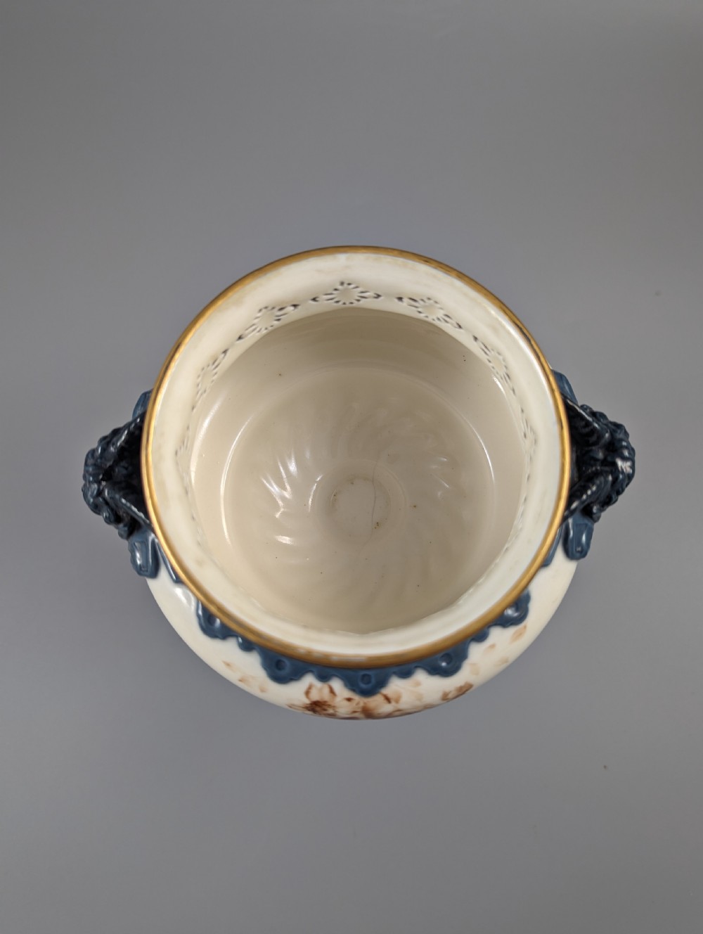 A late Victorian cream and dark blue porcelain pedestal urn decorated with hand-painted sepia floral panels, dark scroll handles, a matching lid, and gilded accents. View VIII