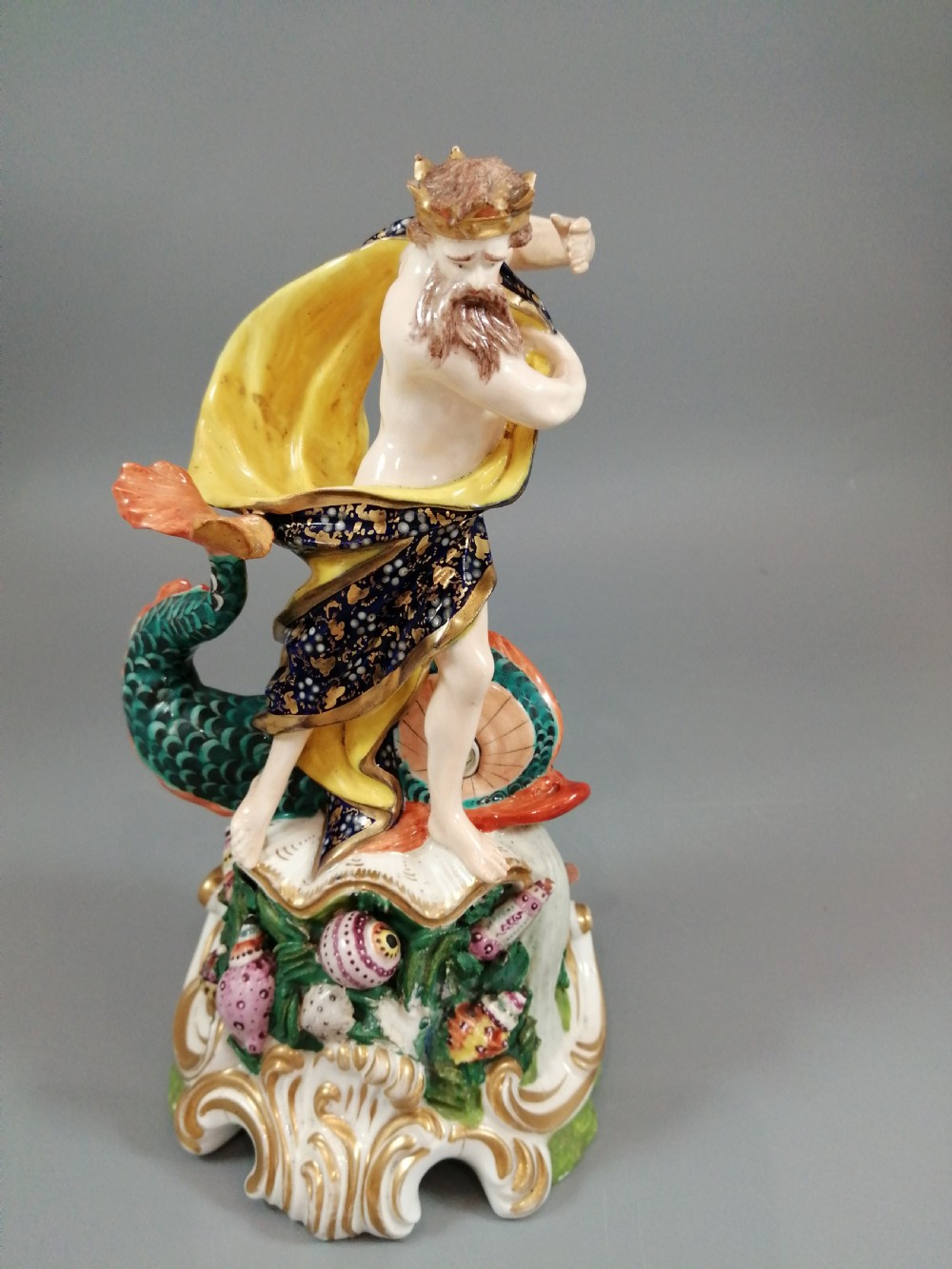 A Bloor Derby porcelain figure of Neptune standing atop a shell and rockwork base with sea creatures, wearing a crown and drapery decorated in gold leaf and blue enamel. View VIII