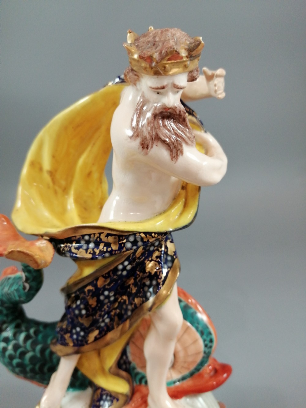 A Bloor Derby porcelain figure of Neptune standing atop a shell and rockwork base with sea creatures, wearing a crown and drapery decorated in gold leaf and blue enamel. View IX