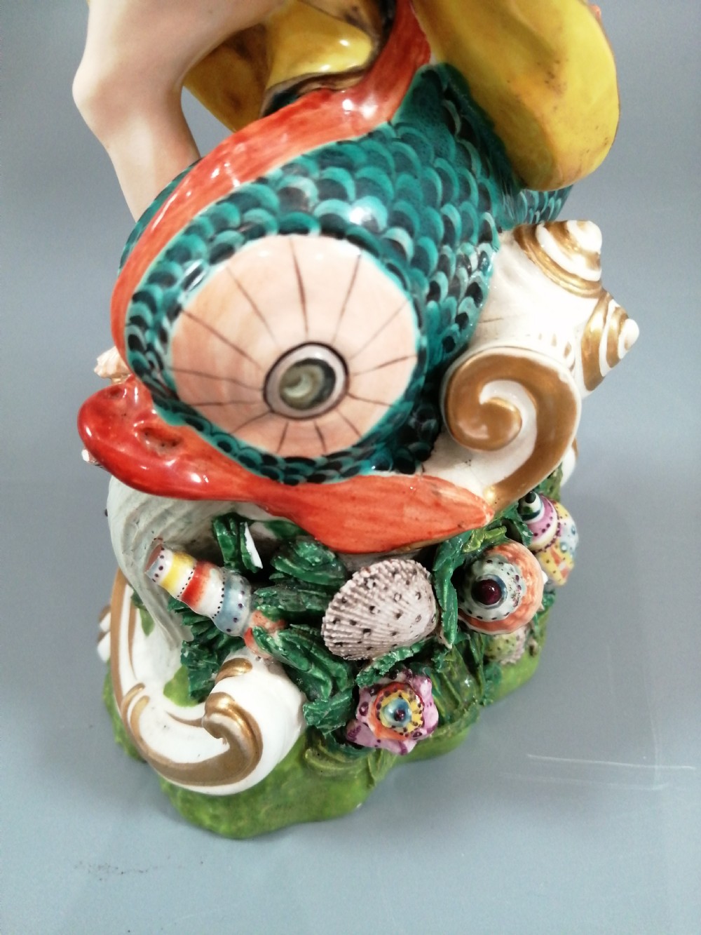 A Bloor Derby porcelain figure of Neptune standing atop a shell and rockwork base with sea creatures, wearing a crown and drapery decorated in gold leaf and blue enamel. View XI