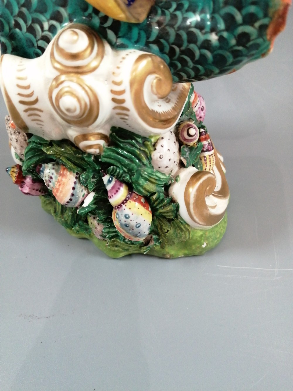 A Bloor Derby porcelain figure of Neptune standing atop a shell and rockwork base with sea creatures, wearing a crown and drapery decorated in gold leaf and blue enamel. View XII